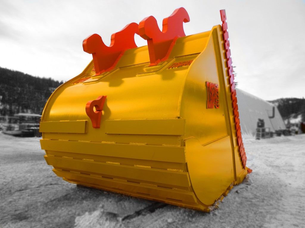 Excavator dig bucket manufactured by Tysea Mfg.  Painted yellow with replaceable orange pin on teeth and bolt on cutting edges