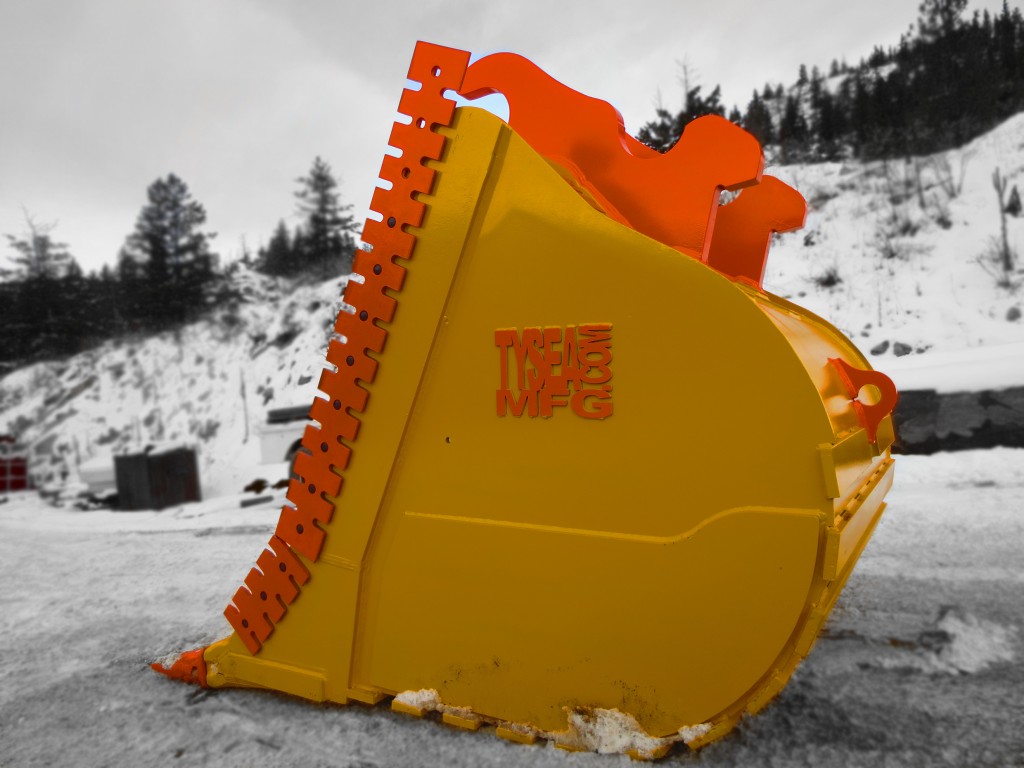 Excavator dig bucket manufactured by Tysea Mfg.  Painted yellow with replaceable pin on teeth and bolt on cutting edges