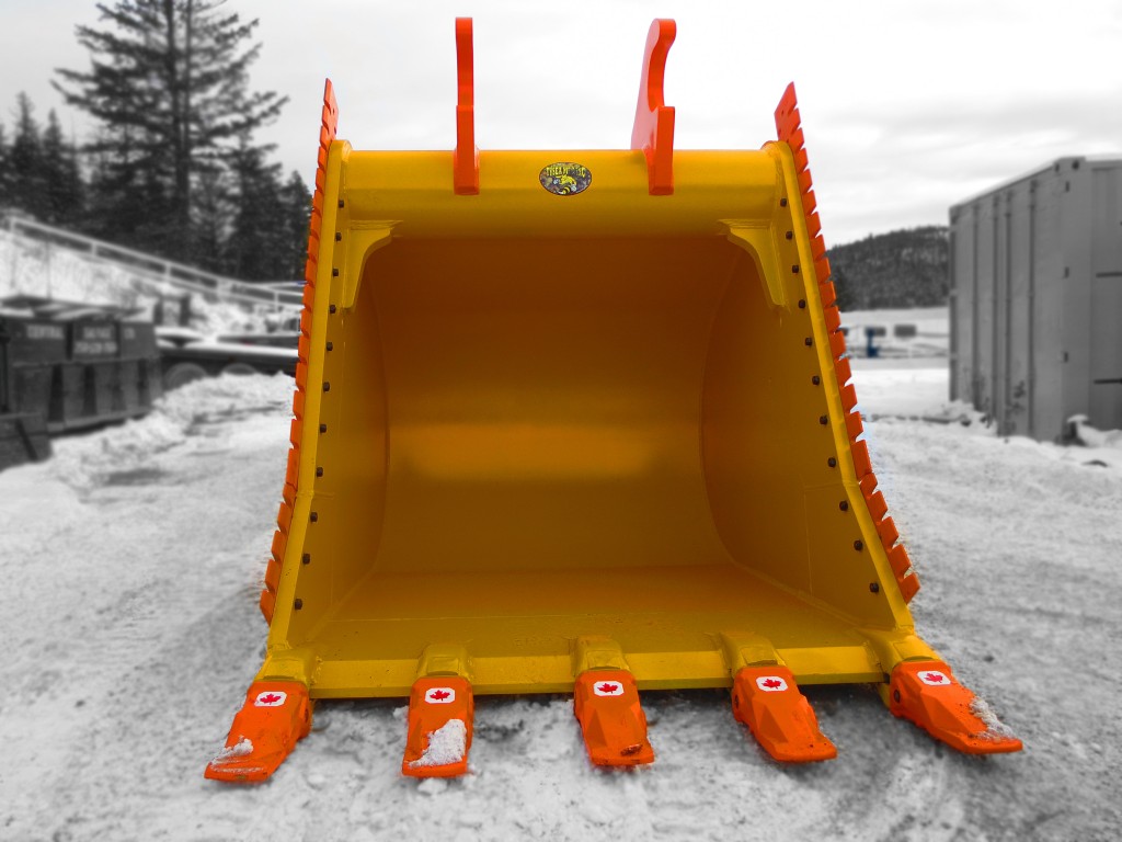 Excavator dig bucket manufactured by Tysea Mfg.  Painted yellow with replaceable pin teeth and bolt on serrated cutting edges