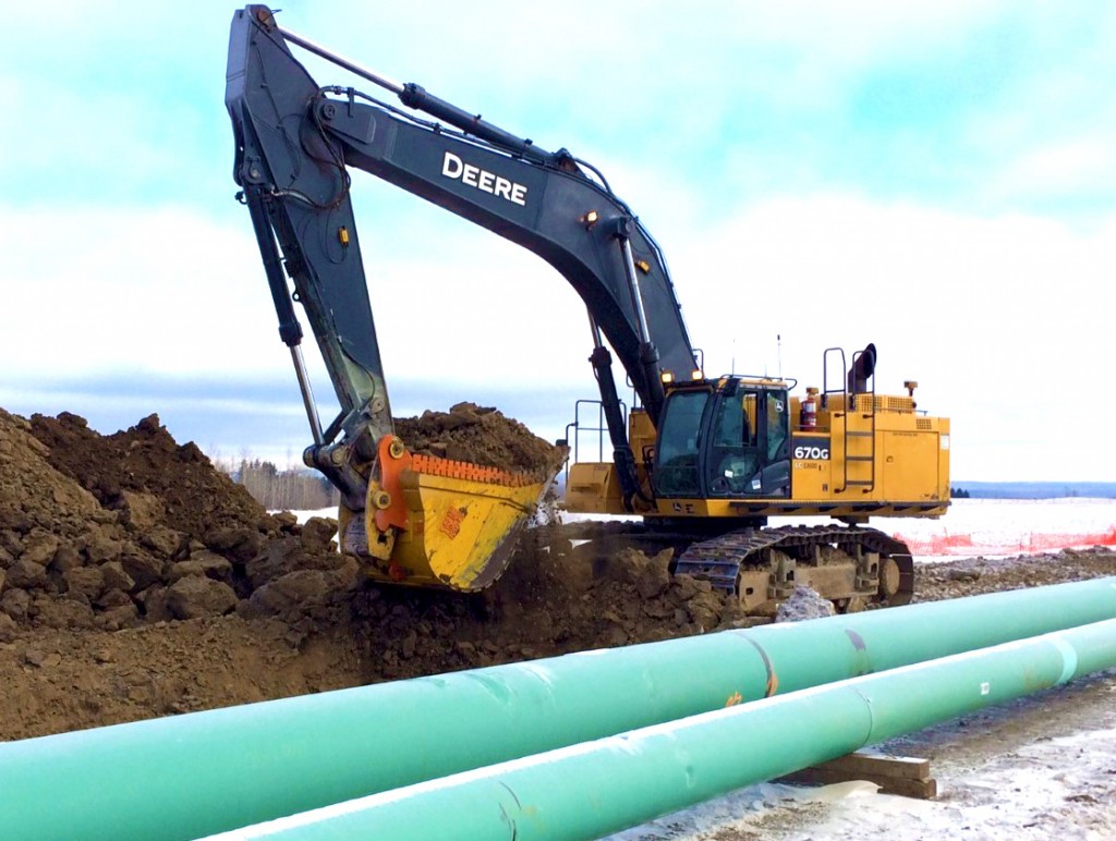 Heavy duty dig bucket installed on John Deere excavator digging dirt next to pipeline