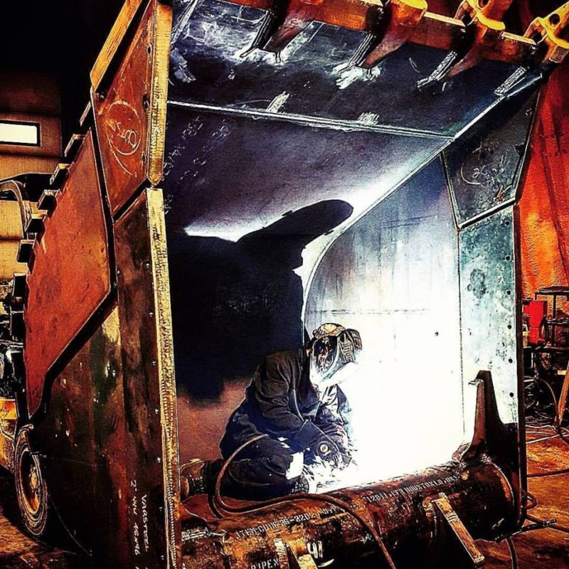 Welder at Tysea Mfg welding inside a huge heavy duty excavator Digging Bucket.