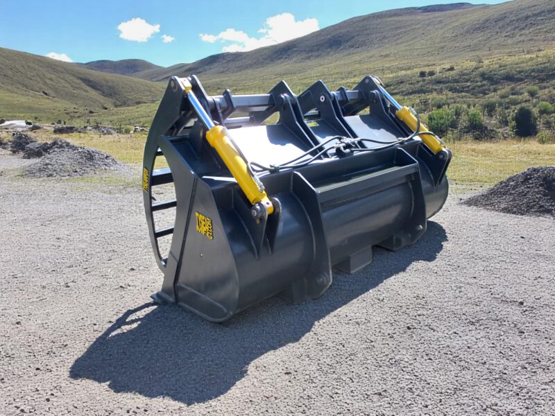 Wheel loader corral bucket sitting in a gravel lot with rolling hills in background