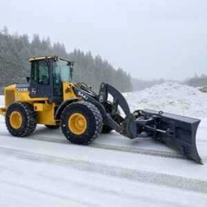 Wheel loader with snow blade attached clearing snow on a paved highway