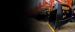 Excavator wrist bucket with Tysea Mfg logo in front of a line up of Hitachi excavators