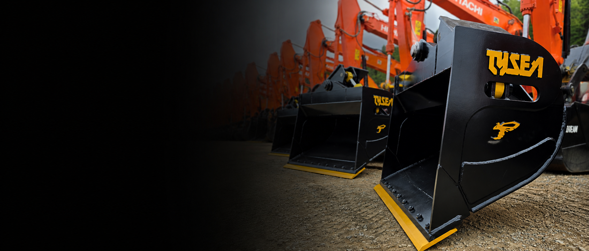 Excavator wrist bucket with Tysea Mfg logo in front of a line up of Hitachi excavators
