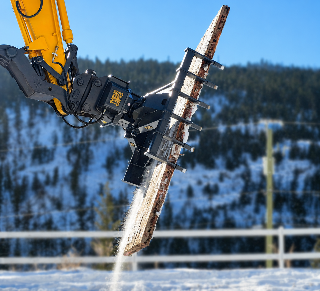 Excavator mat grapple holding a wood rig mat in the air in a wintery setting